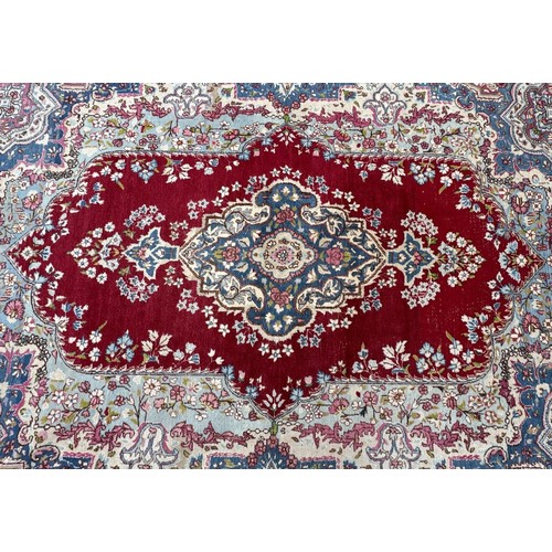 1763 - An old  Kirman carpet with a floral elongated medallion on a crimson field and blue floral borders 3... 