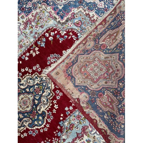 1763 - An old  Kirman carpet with a floral elongated medallion on a crimson field and blue floral borders 3... 