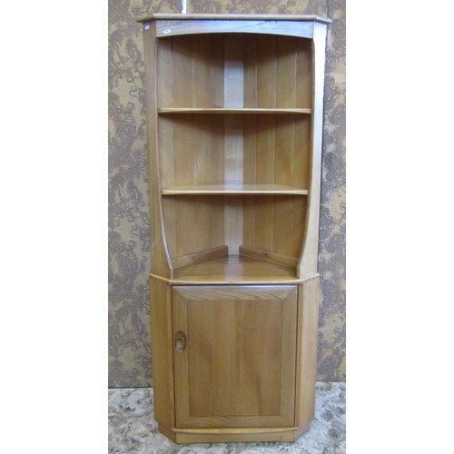 1209 - A pale Ercol floor-standing corner cupboard with open shelves over a cupboard base with hinged panel... 