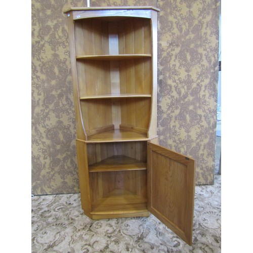 1209 - A pale Ercol floor-standing corner cupboard with open shelves over a cupboard base with hinged panel... 