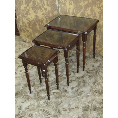 1308 - A graduating nest of three mahogany occasional tables with strung borders and shaped tops, raised on... 