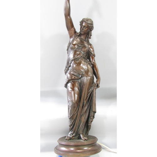 451 - A bronzed metal table lamp in the form of a classical woman holding aloft a lamp, raised on a circul... 