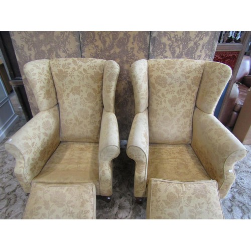 1350 - A matched pair of Georgian style upholstered wing armchairs, with golden floral covers raised on tur... 