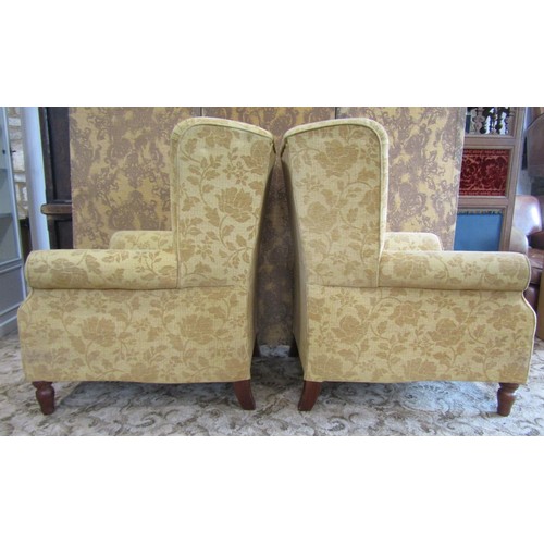 1350 - A matched pair of Georgian style upholstered wing armchairs, with golden floral covers raised on tur... 