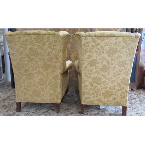 1350 - A matched pair of Georgian style upholstered wing armchairs, with golden floral covers raised on tur... 