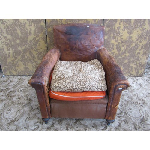 1365 - A rustic continental tan leather armchair, raised on bun supports and castors