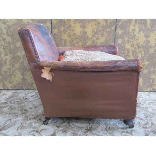 1365 - A rustic continental tan leather armchair, raised on bun supports and castors