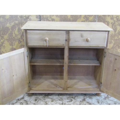 1368 - A pale pine cupboard fitted with two drawers over a pair of panelled cupboard doors revealing a shel... 