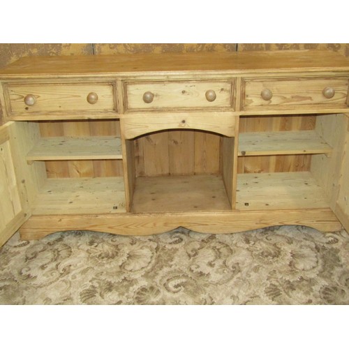 1370 - A pale pine dresser base fitted with three drawers over a pair of panelled cupboards flanking a cent... 