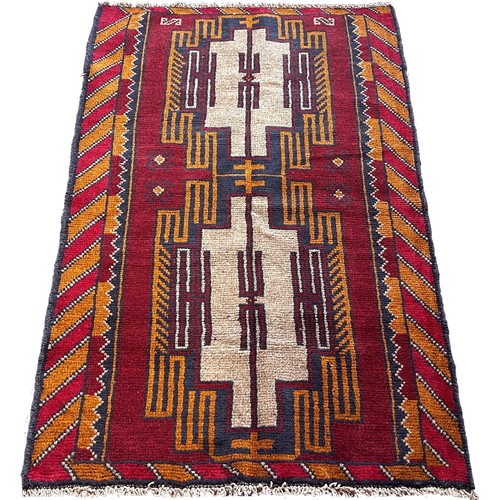 1790 - A Baluchi rug with two geometric interlocking panels on a red ground 136cm x 87cm approximately