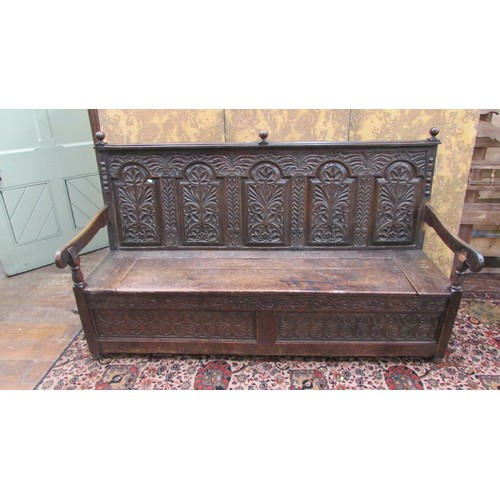 1454 - An antique oak box settle with repeating carved detail, the seat incorporating a rising lid, 185cm l... 