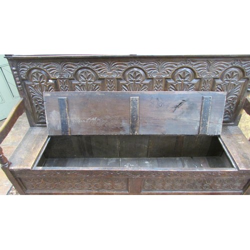 1454 - An antique oak box settle with repeating carved detail, the seat incorporating a rising lid, 185cm l... 