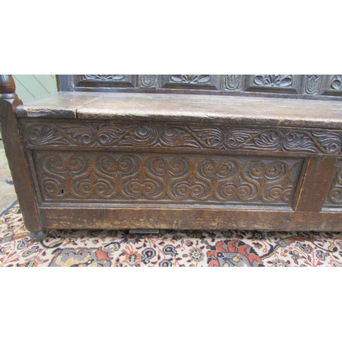 1454 - An antique oak box settle with repeating carved detail, the seat incorporating a rising lid, 185cm l... 