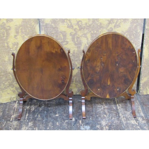 1473 - A close matched pair of Georgian style toilet mirrors in walnut, the oval mirror plates within skele... 