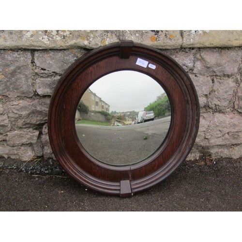 1425 - A circular stained oak framed convex wall mirror in the Art Deco style, 54cm diameter.