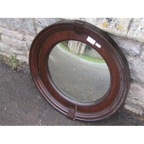 1425 - A circular stained oak framed convex wall mirror in the Art Deco style, 54cm diameter.