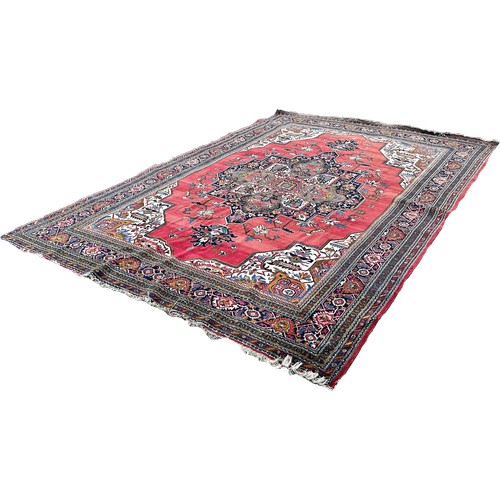 1749 - A Middle  Eastern carpet with an expansive stylised floral central medallion on a pink ground, 390cm... 