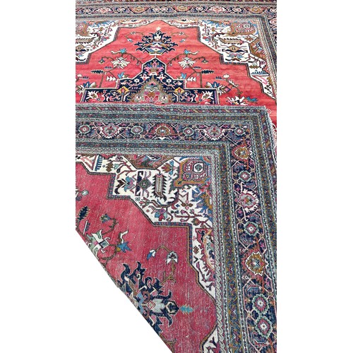 1749 - A Middle  Eastern carpet with an expansive stylised floral central medallion on a pink ground, 390cm... 