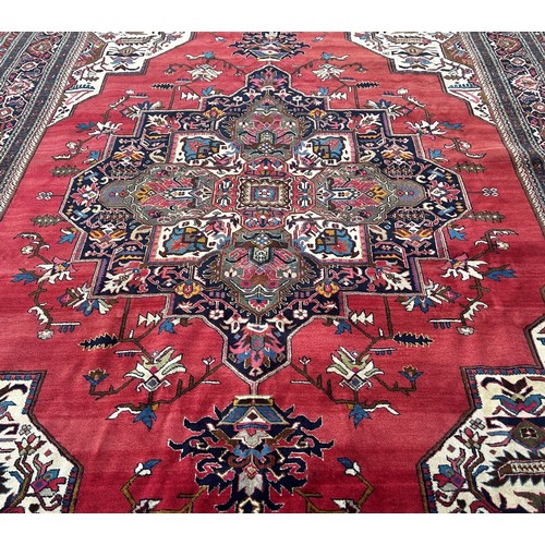 1749 - A Middle  Eastern carpet with an expansive stylised floral central medallion on a pink ground, 390cm... 