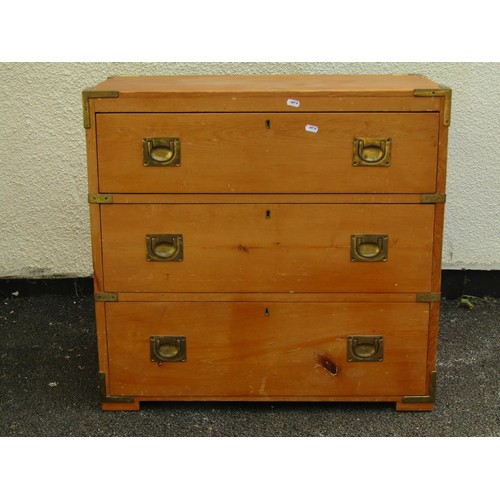 1556A - A pale pine chest of three drawers, in the campaign / military style with flush brass handles and ap... 