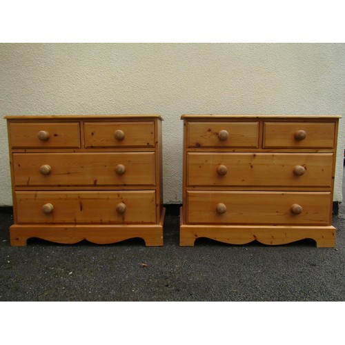 1557 - A pair of pale pine chests of two short and two long drawers, each with turned handles and shaped ap... 