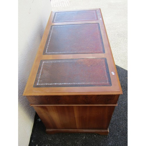 1565 - A reproduction leather-topped yew wood pedestal desk fitted with nine drawers, 75cm high, 121 x 60cm