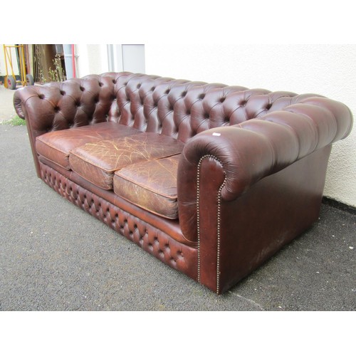 1565A - A brown leather chesterfield three seat sofa, with rolled and buttoned arms and back