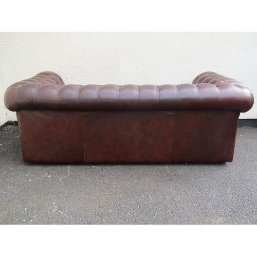 1565A - A brown leather chesterfield three seat sofa, with rolled and buttoned arms and back