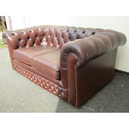 1566 - A brown leather chesterfield two seat sofa, with buttoned rolled arms and back and studded borders