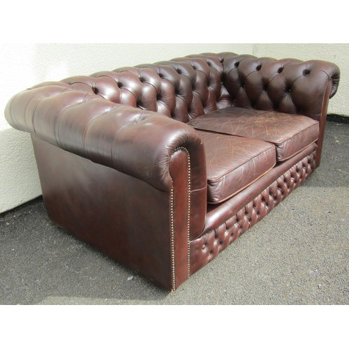 1566 - A brown leather chesterfield two seat sofa, with buttoned rolled arms and back and studded borders