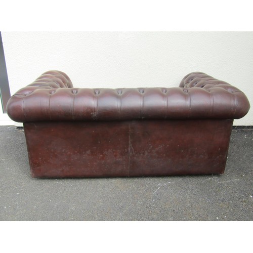 1566 - A brown leather chesterfield two seat sofa, with buttoned rolled arms and back and studded borders