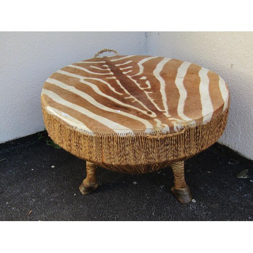 1570 - An African Zebra skin drum table, on hoof supports, 55cm high, 87cm diameter.