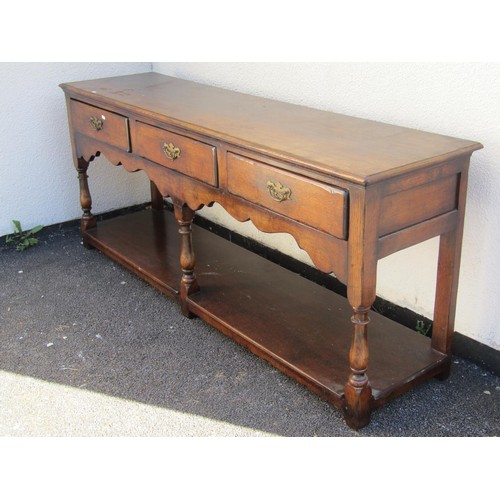 1573 - A George III design oak dresser base, fitted with three drawers over a shaped apron and platform bas... 