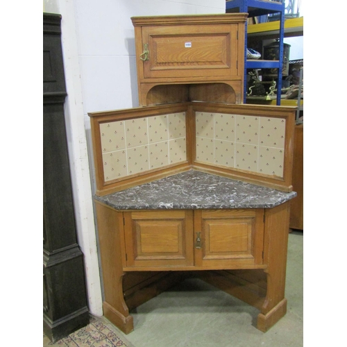 1151 - A early 20th century oak corner washstand in the Arts & Crafts style, with marble top and tiles pane... 