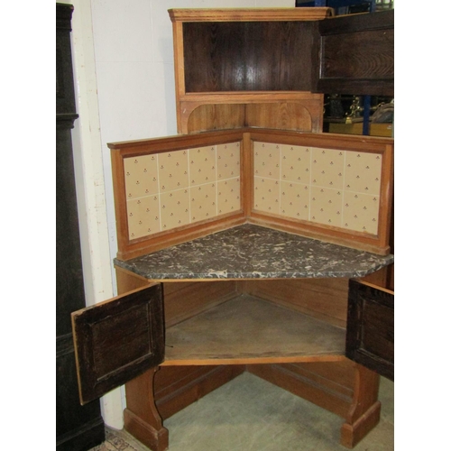 1151 - A early 20th century oak corner washstand in the Arts & Crafts style, with marble top and tiles pane... 