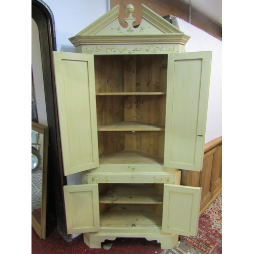 1429 - An over-painted floor standing two-sectional corner cupboard with broken pediment over hinged panell... 