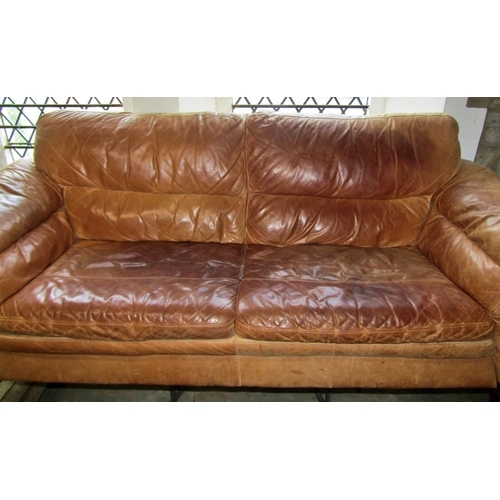 1358 - A weathered tan leather two seat sofa, 217cm wide.