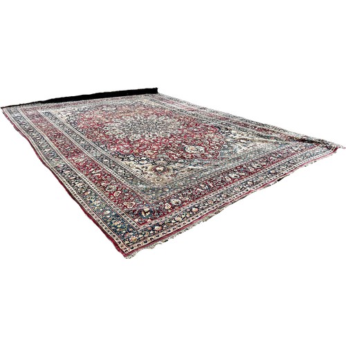 1744 - A large Middle Eastern country house carpet with an all over floral pattern on a predominantly red g... 