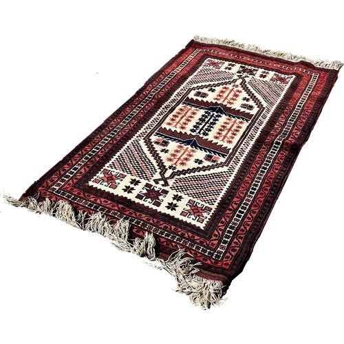 1743 - A Kazak type carpet with an elongated central panel on a cream ground, 180cm x 110cm approximately