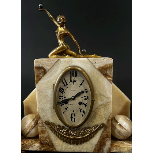 412 - An art deco clock garniture in onyx with oval dial surmounted by a female in out stretched kneeling ... 