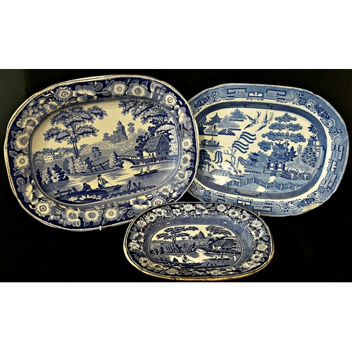 75 - Three 19th century meat platters, two with rural fishing scenes, the third in a Willow pattern, 46cm... 