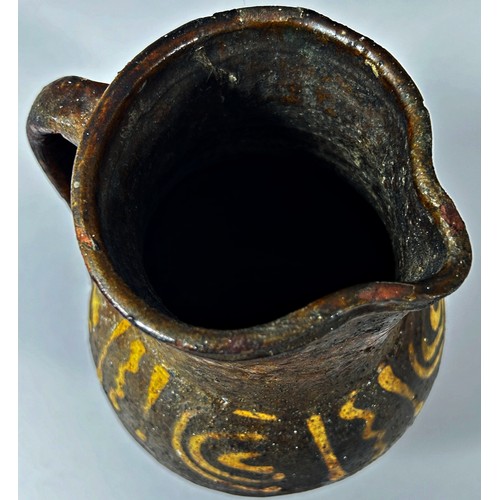 124 - An early pottery jug with loop handle and slipware detail, 19cm high