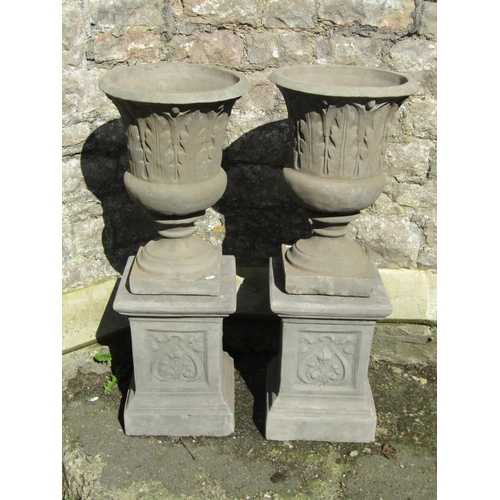 1014 - A pair of cast composition stone trumpet shaped garden urns with relief detail, raised on square cut... 