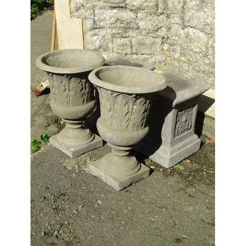 1014 - A pair of cast composition stone trumpet shaped garden urns with relief detail, raised on square cut... 