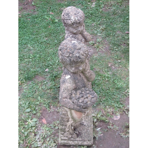 1021 - A matched pair of cast composition stone garden ornaments in the form of standing cherubs clutching ... 