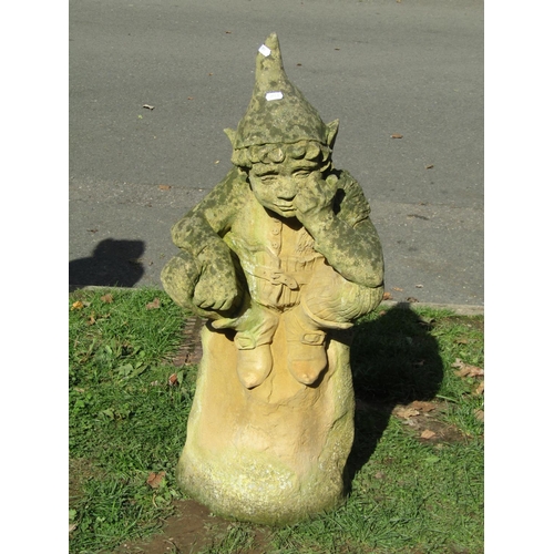 1023 - A weathered cast composition stone garden ornament in the form of a contemplating pixie sat on a tre... 