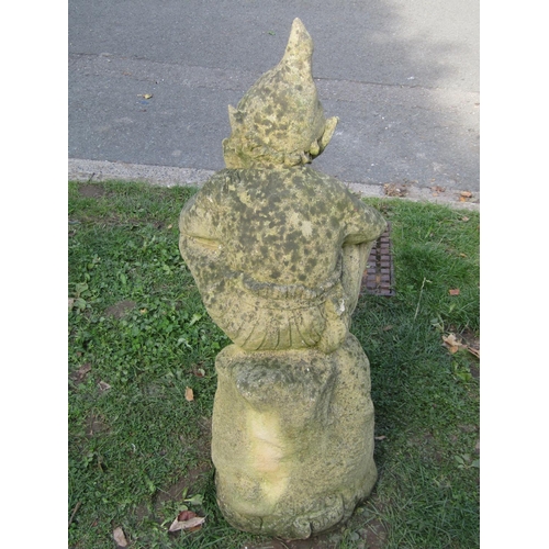 1023 - A weathered cast composition stone garden ornament in the form of a contemplating pixie sat on a tre... 