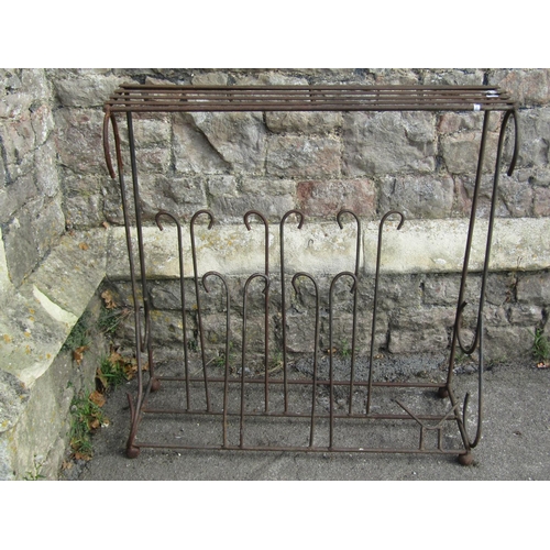 1031 - A weathered iron work boot stand/rack with simple open scroll detail beneath a strap work top/shelf,... 