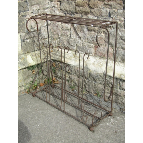 1031 - A weathered iron work boot stand/rack with simple open scroll detail beneath a strap work top/shelf,... 