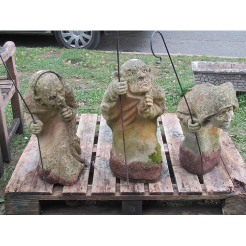 1061 - Three weathered cast composition stone garden ornaments in the form of goblins in varying poses but ... 